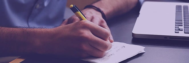 UG Images 318x106-40 man writing notes in notebook next to laptop